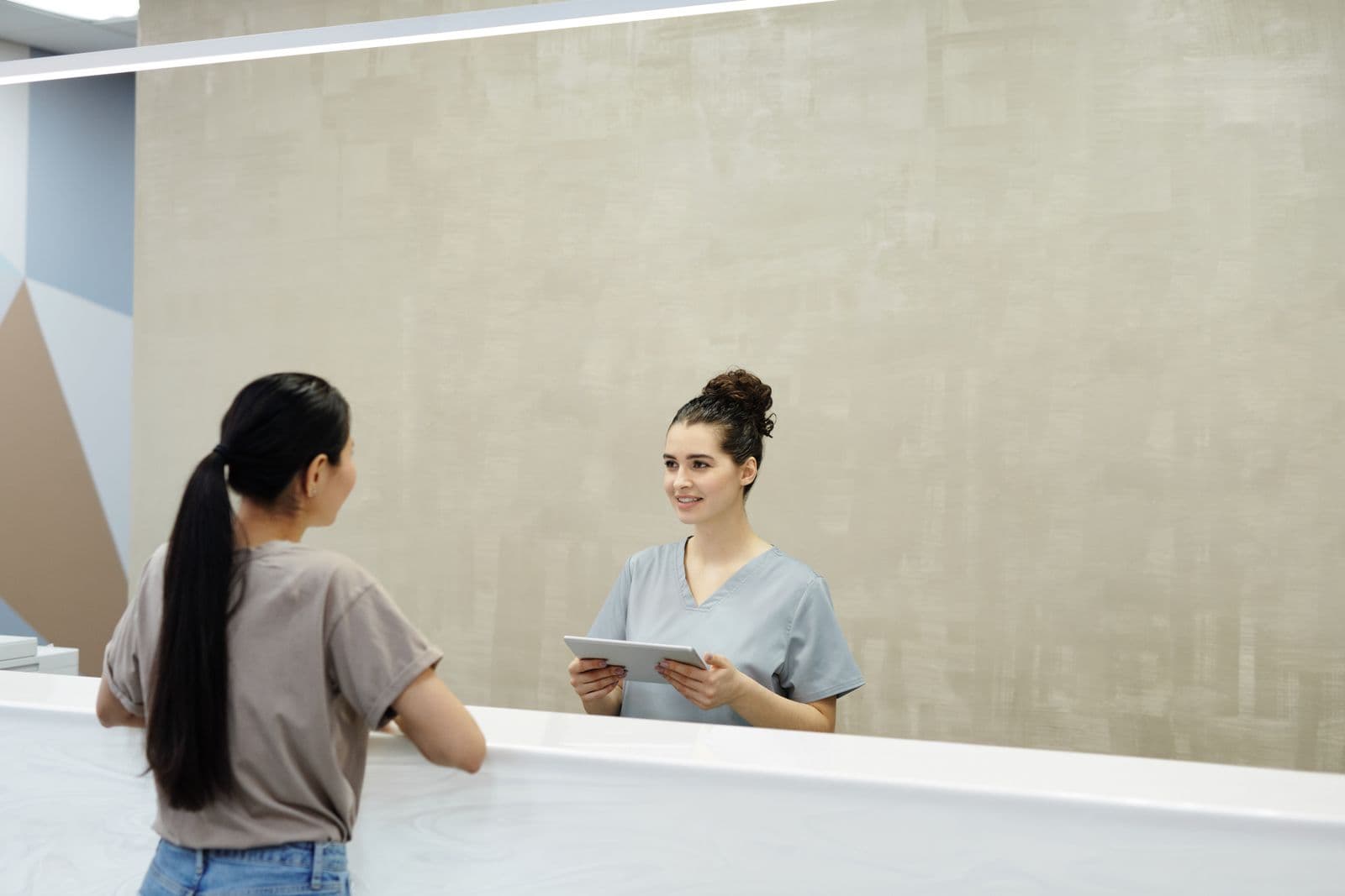 Recepcionista conversa com uma paciente no balcão da clínica
